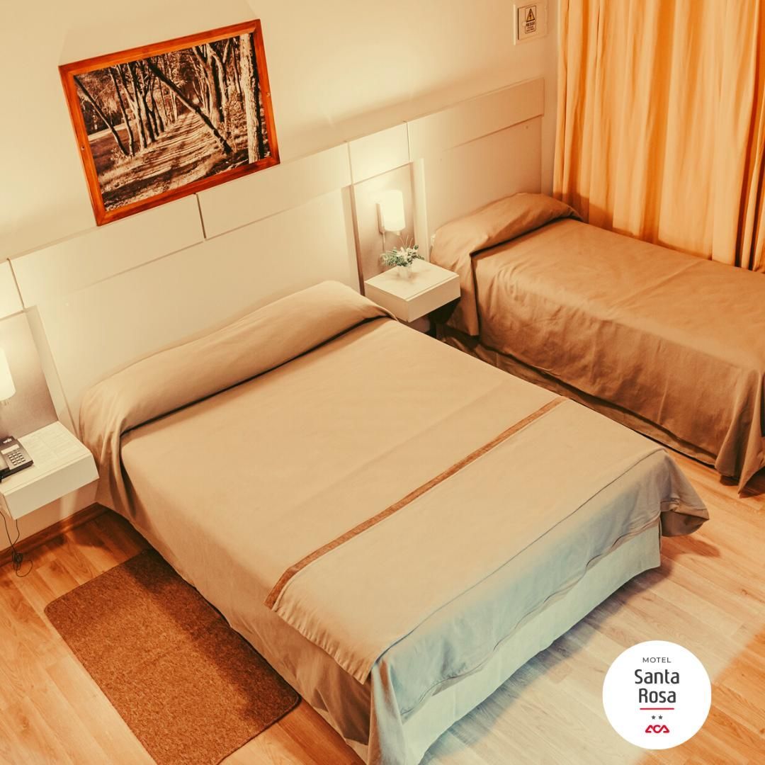 Bedroom with two beds, light-colored bedding, wooden floors, art on the wall, and beige curtains.
