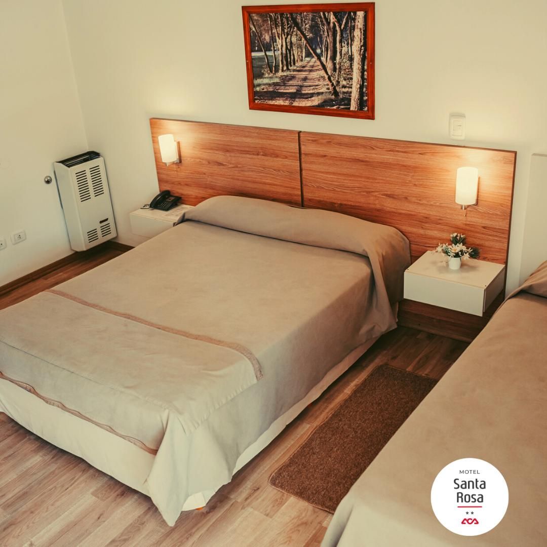 Hotel room with two beds, neutral tones, wooden headboard, wall art, bedside tables, and heater.