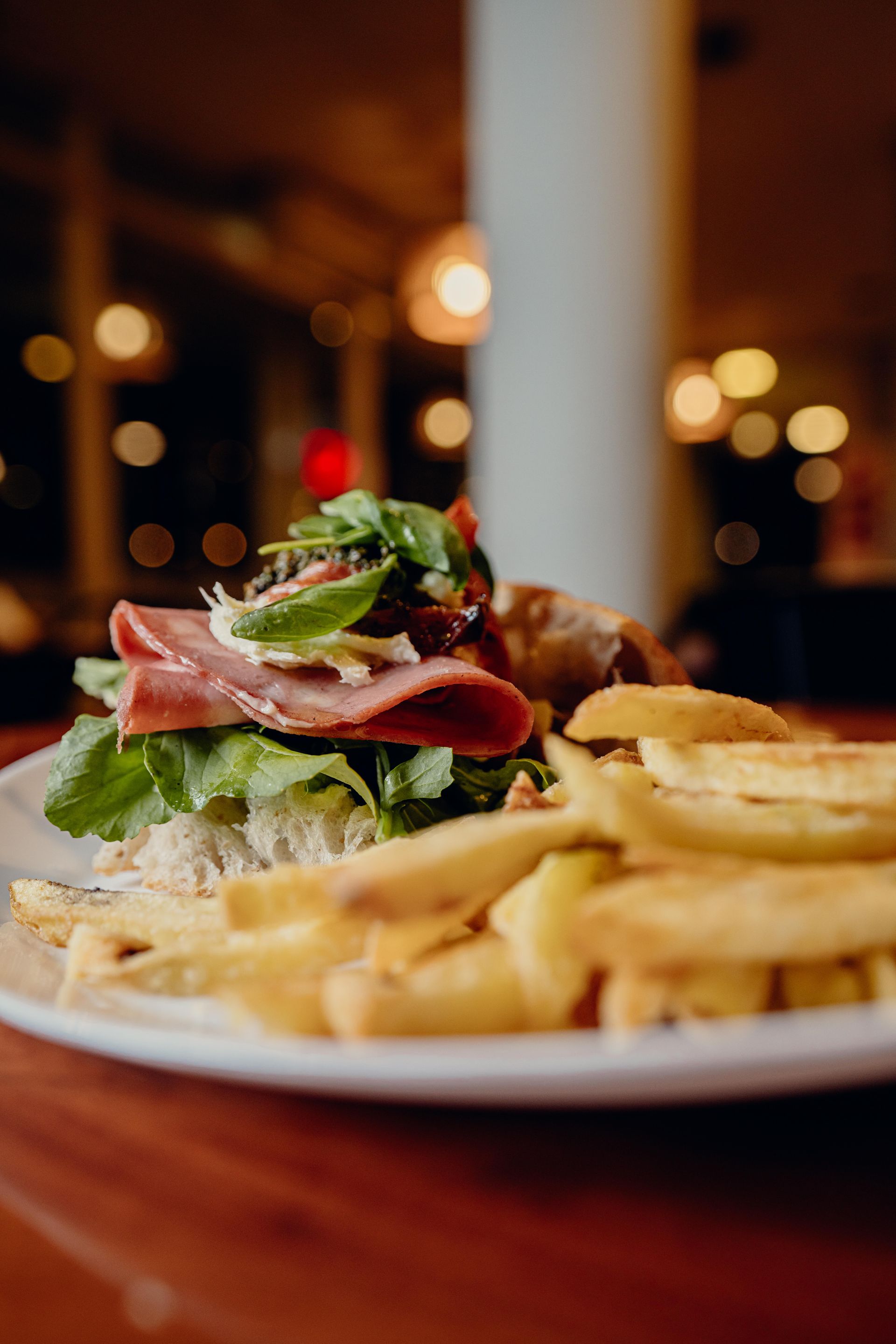 Sándwich con patatas fritas en un plato en un restaurante; comida, fondo borroso.