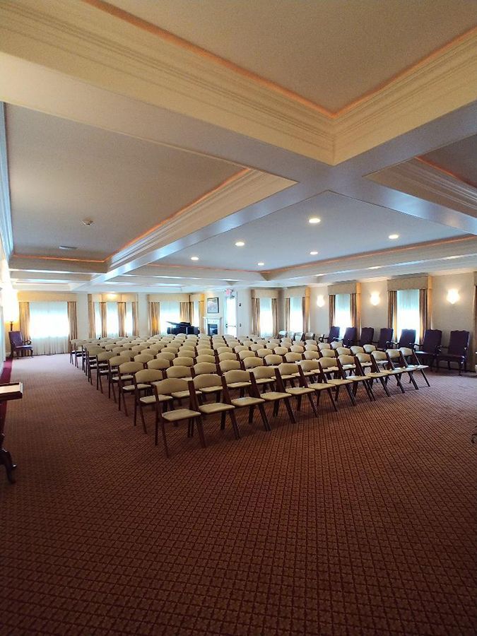 Rows of chairs face forward in a large, carpeted room; likely a conference or event setting.