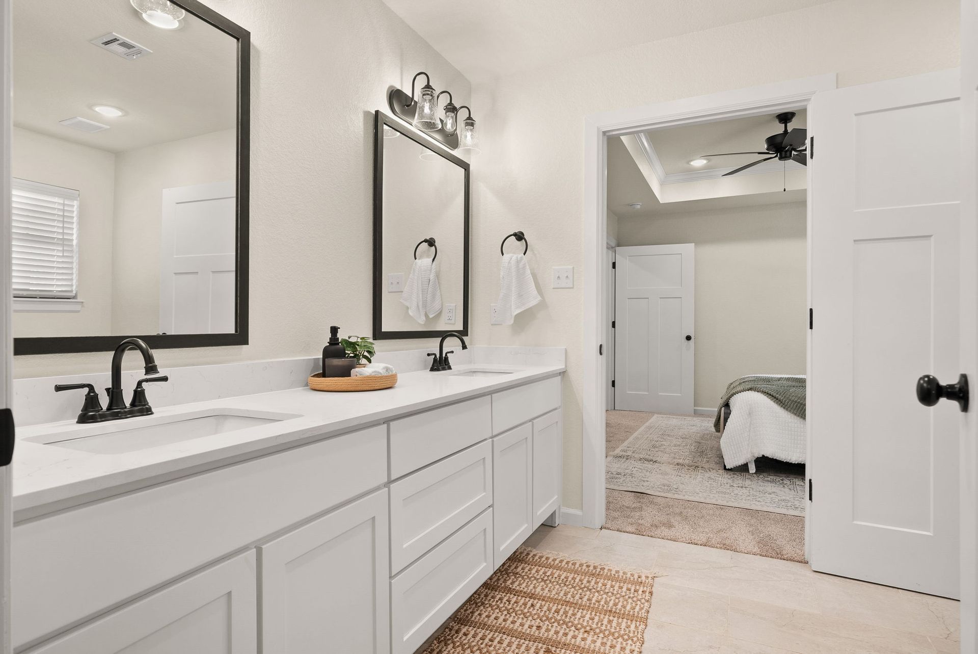 A bathroom with two sinks , two mirrors , and a ceiling fan.