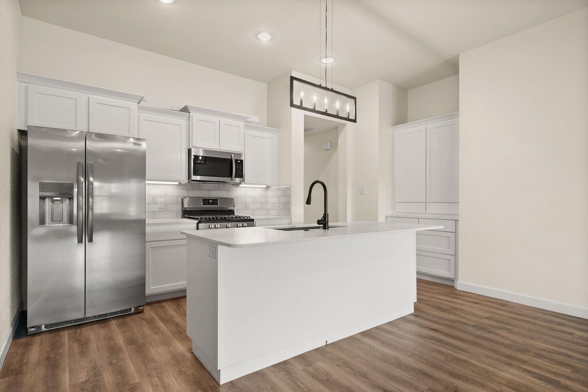 A kitchen with white cabinets , stainless steel appliances , and a large island.