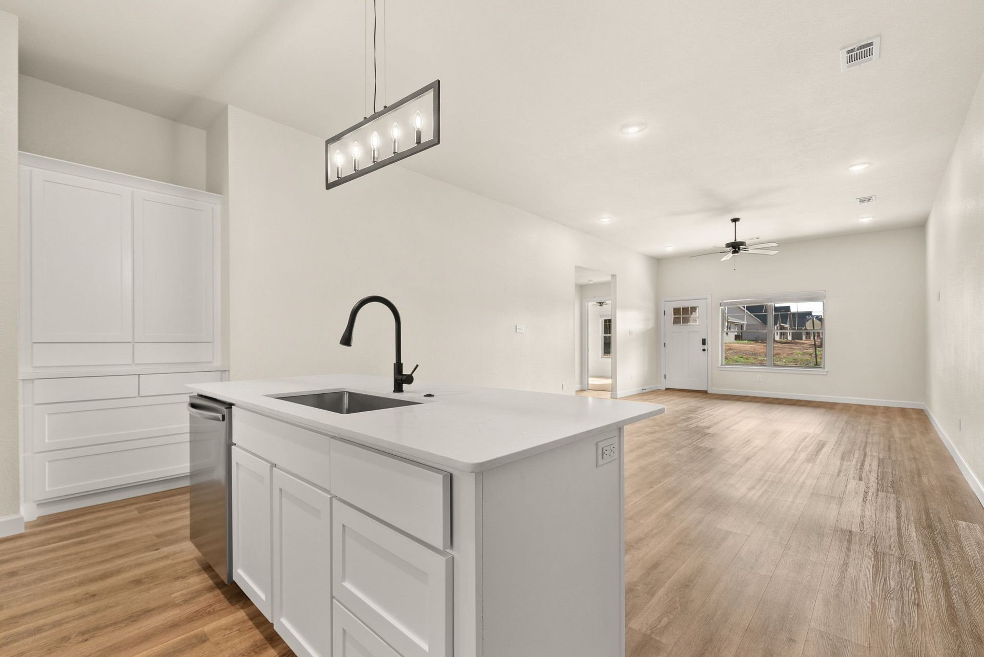 A kitchen with white cabinets , stainless steel appliances , and hardwood floors.