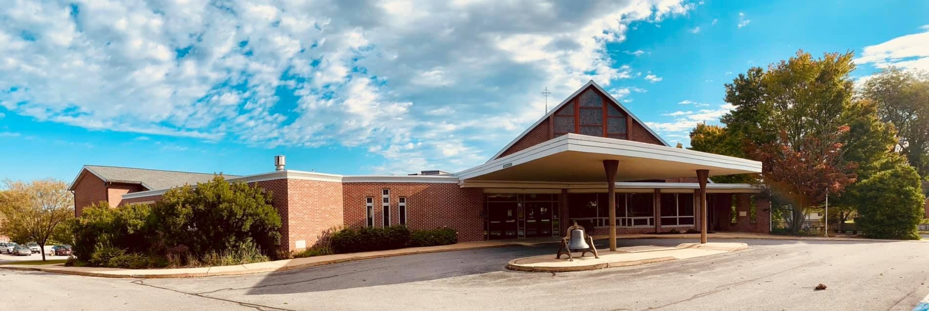 A large brick building with a lot of windows and trees in front of it.