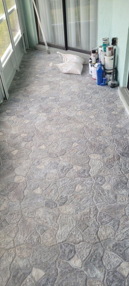 Gray floor with stone-like pattern, next to windows and a stack of construction supplies.