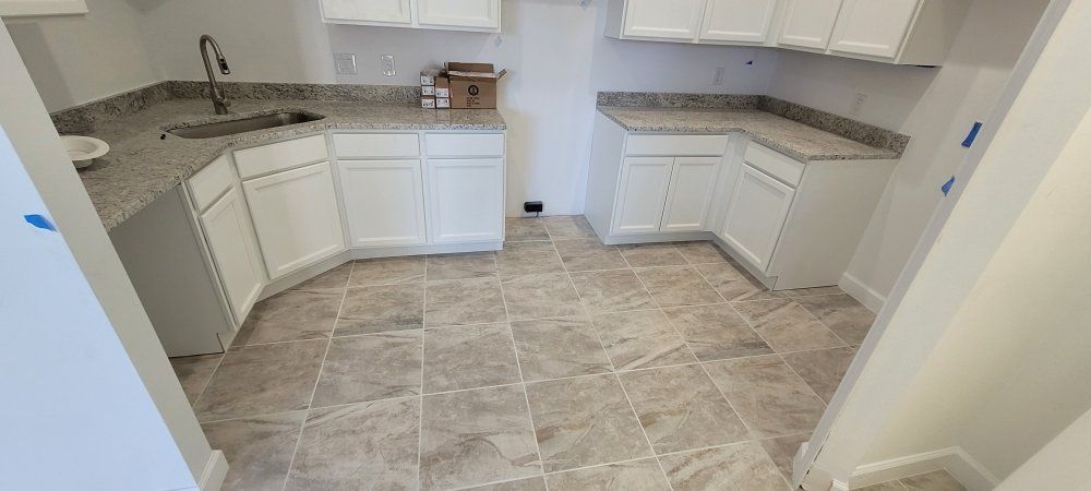 A newly renovated kitchen with white cabinets, granite countertops, and tiled floor.