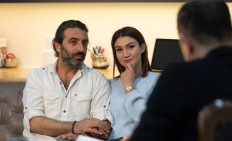 A man and a woman are sitting on a couch talking to a woman.