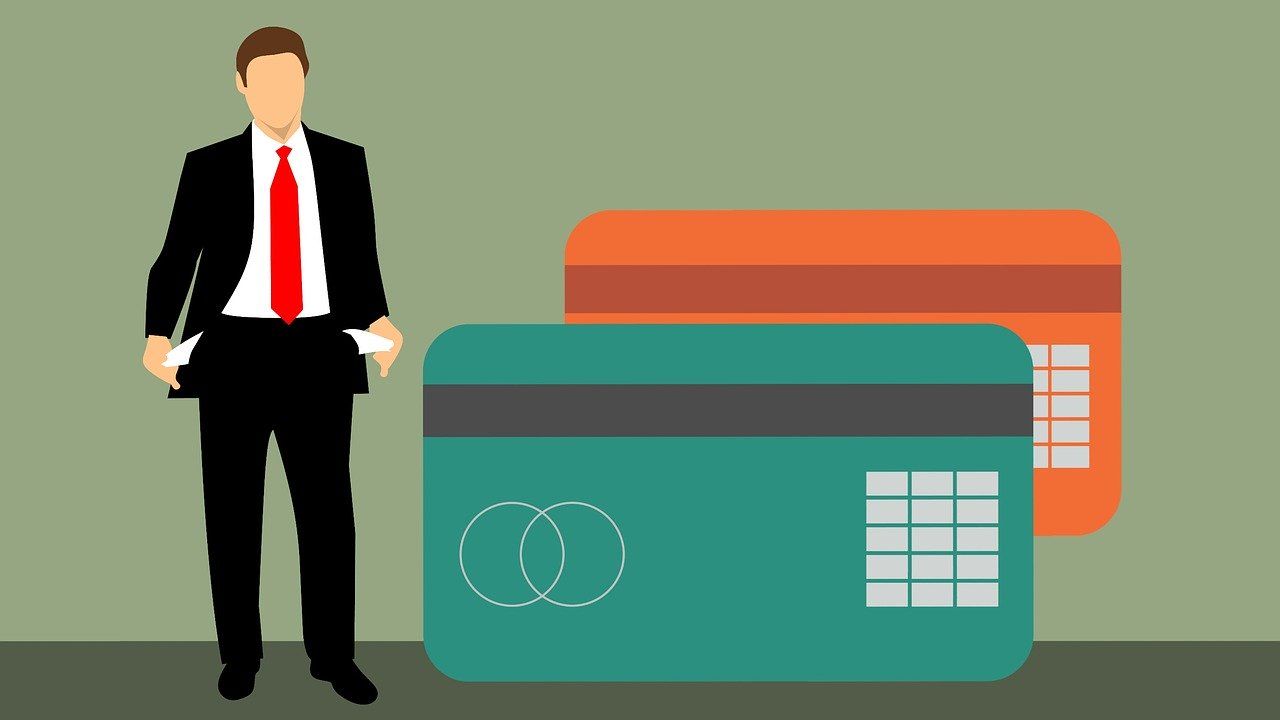 A man in a suit and tie is standing next to two credit cards.