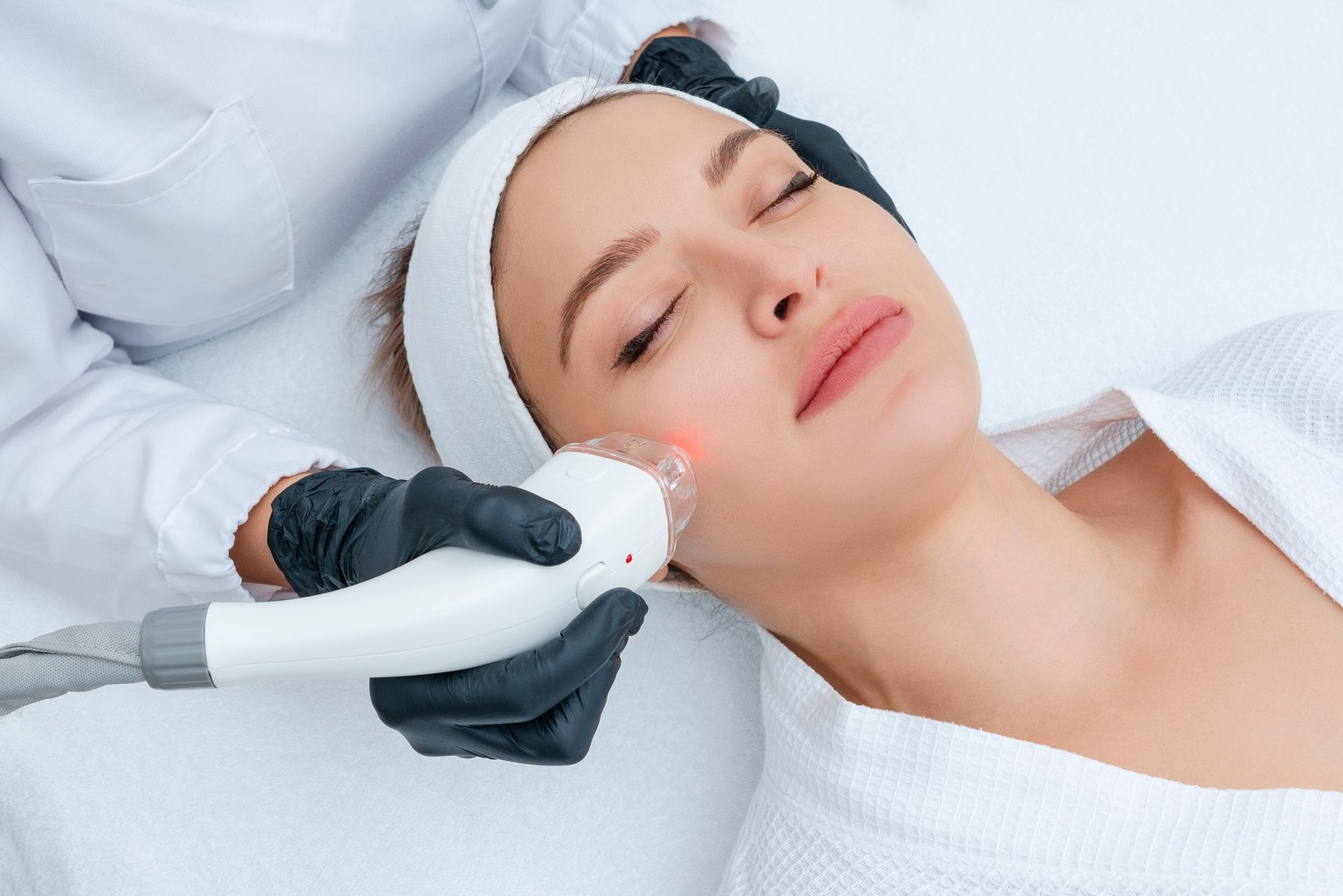 Cosmetic procedure in progress as gloved hands inject above a woman’s eyebrow in a clinic