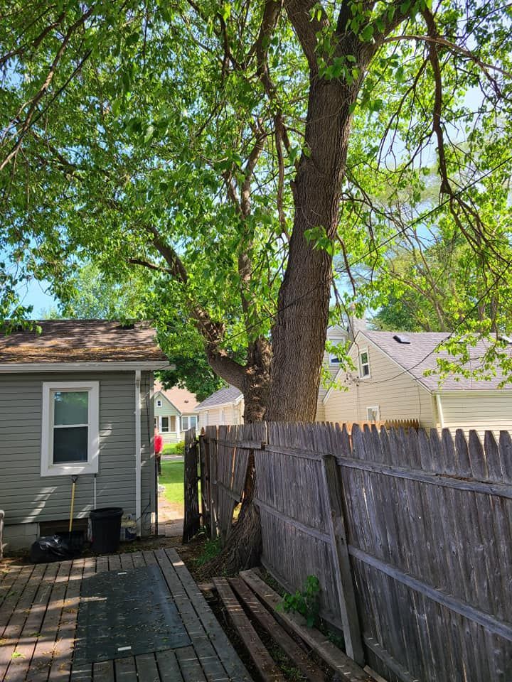 A house with a wooden fence and a tree in front of it.