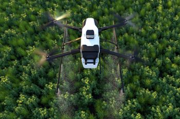 An aerial view of a drone spraying a field of trees.