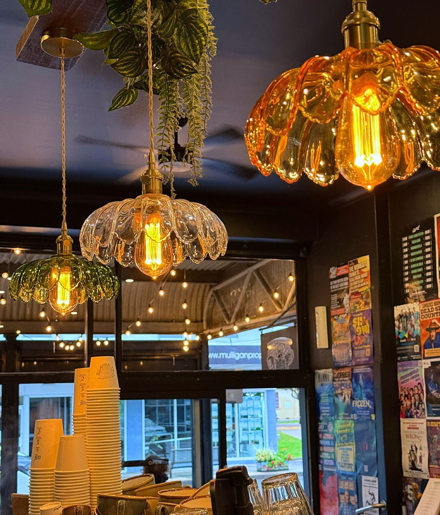 Decorative glass pendant lights hang in a cafe, reflected in a window — Drop In Espresso Bar in Wallsend, NSW