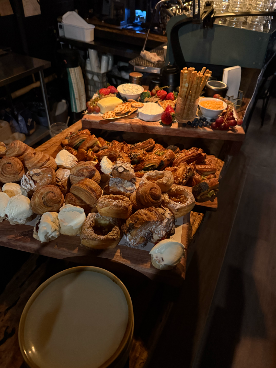 A charcuterie board with pastries, cheese, and fruit, displayed on a wooden table — Drop In Espresso Bar in Wallsend, NSW