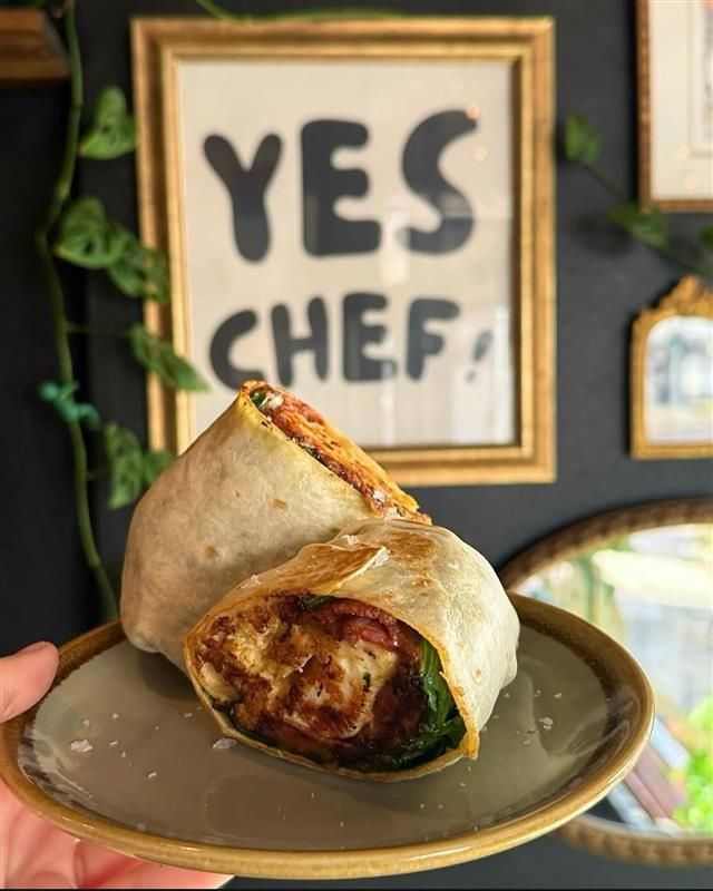 Close-up of a wrap sandwich on a plate, held in a hand; 