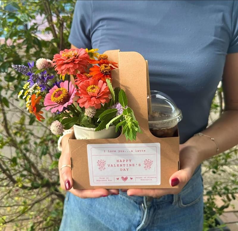 Woman holding a carrier with flowers, coffee, and a Valentine's Day sticker — Drop In Espresso Bar in Wallsend, NSW