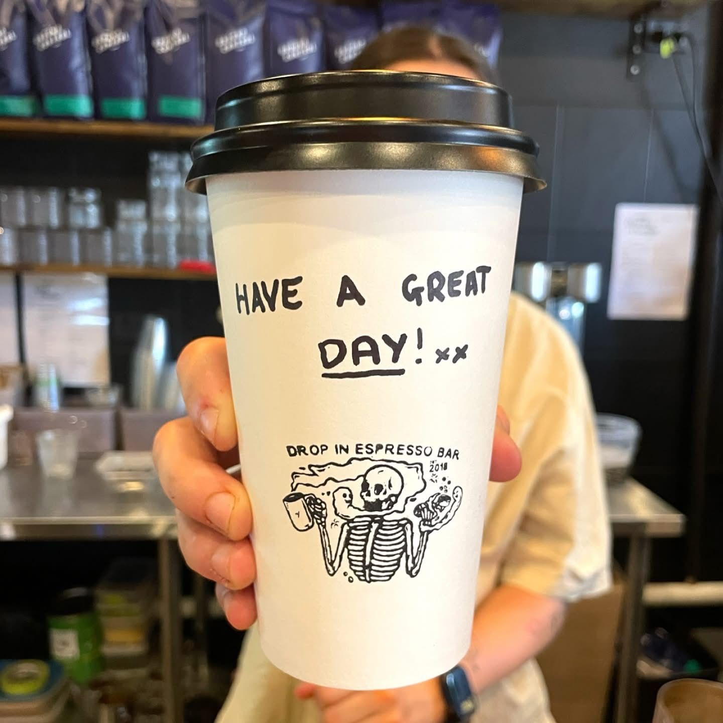 Person holding a coffee cup that says
