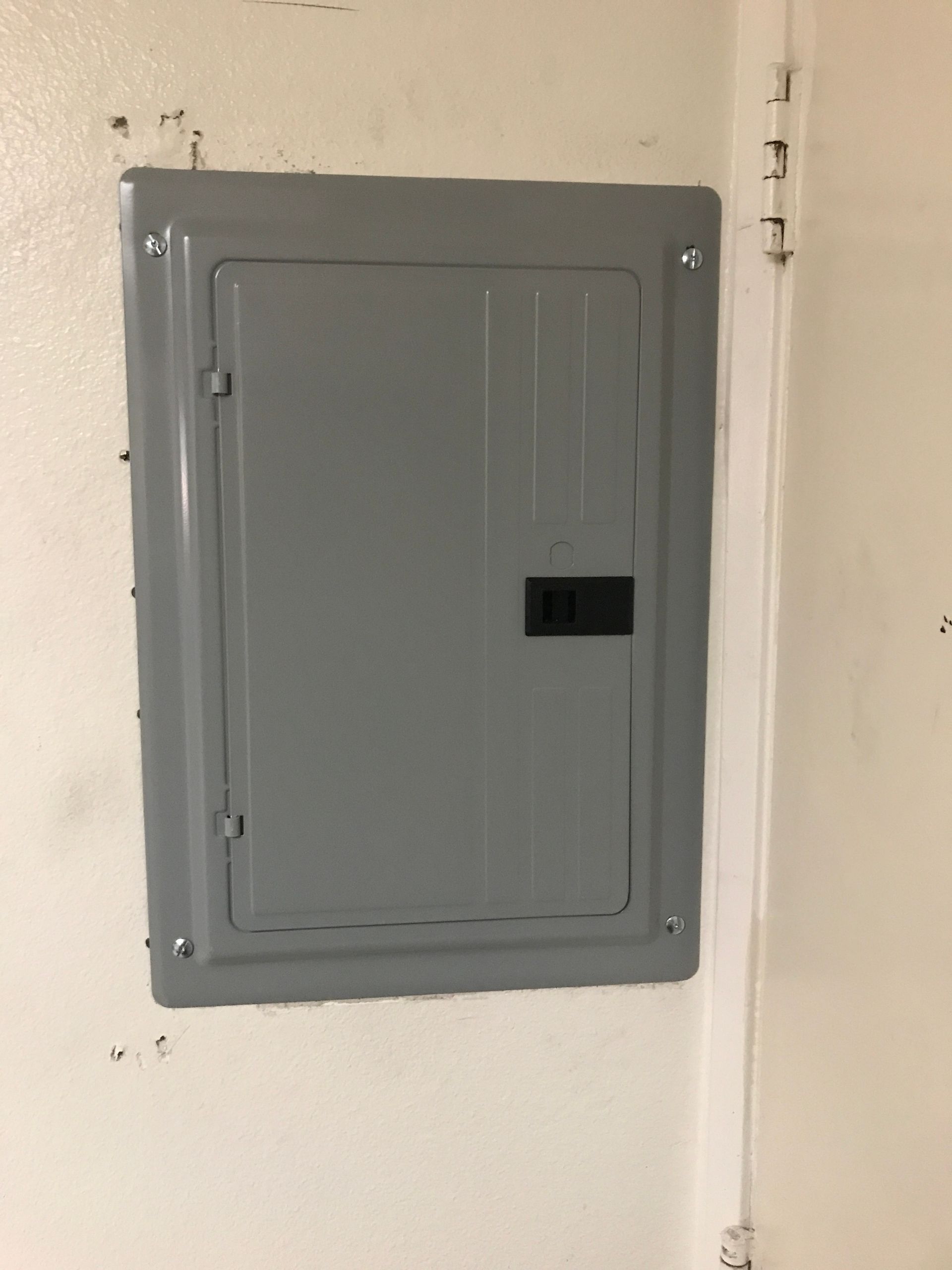 Gray electrical panel mounted on a white wall.