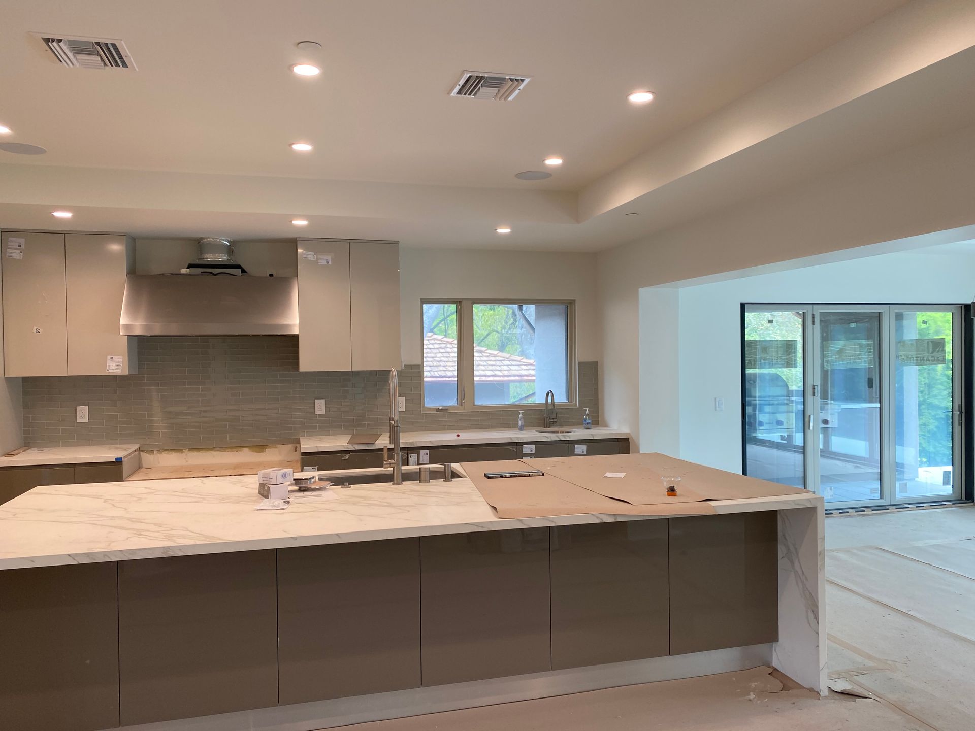 Modern kitchen with neutral cabinets, island, countertops, and windows, and sliding doors.