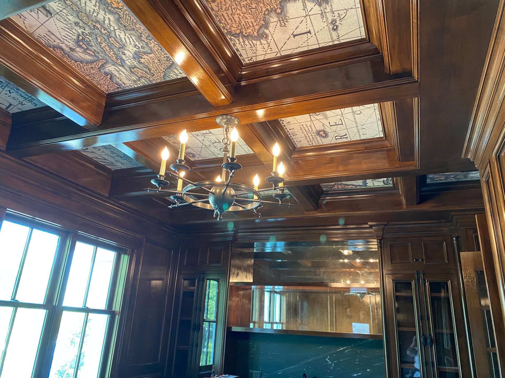 Ornate room with a chandelier, wood-paneled walls, and a patterned ceiling.