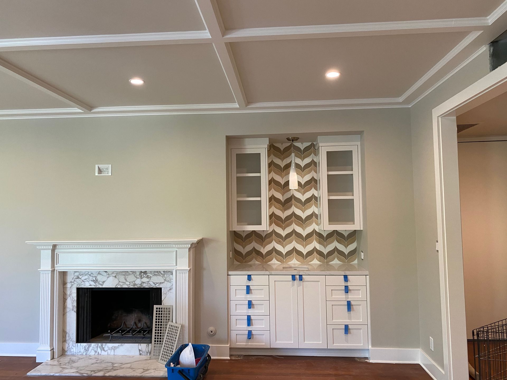 Living room with a white fireplace and built-in bar with chevron tile backsplash.