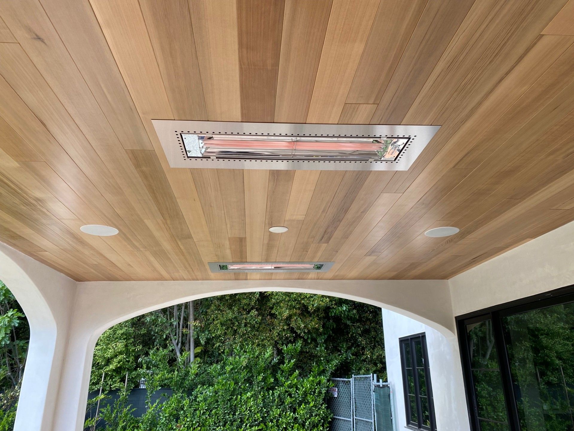 Wooden ceiling with two recessed infrared heaters and two recessed speakers.