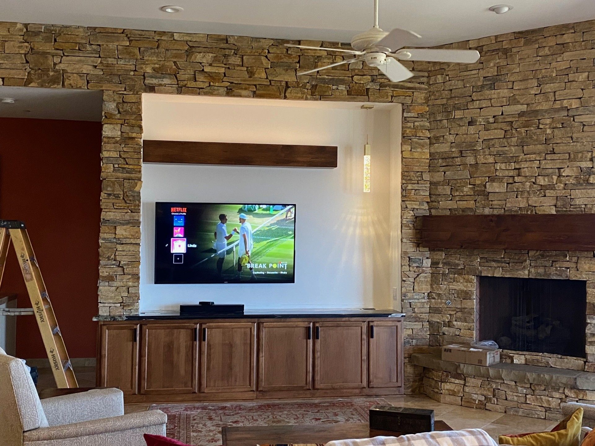 Living room with stone walls, built-in TV, fireplace, and wooden cabinets.
