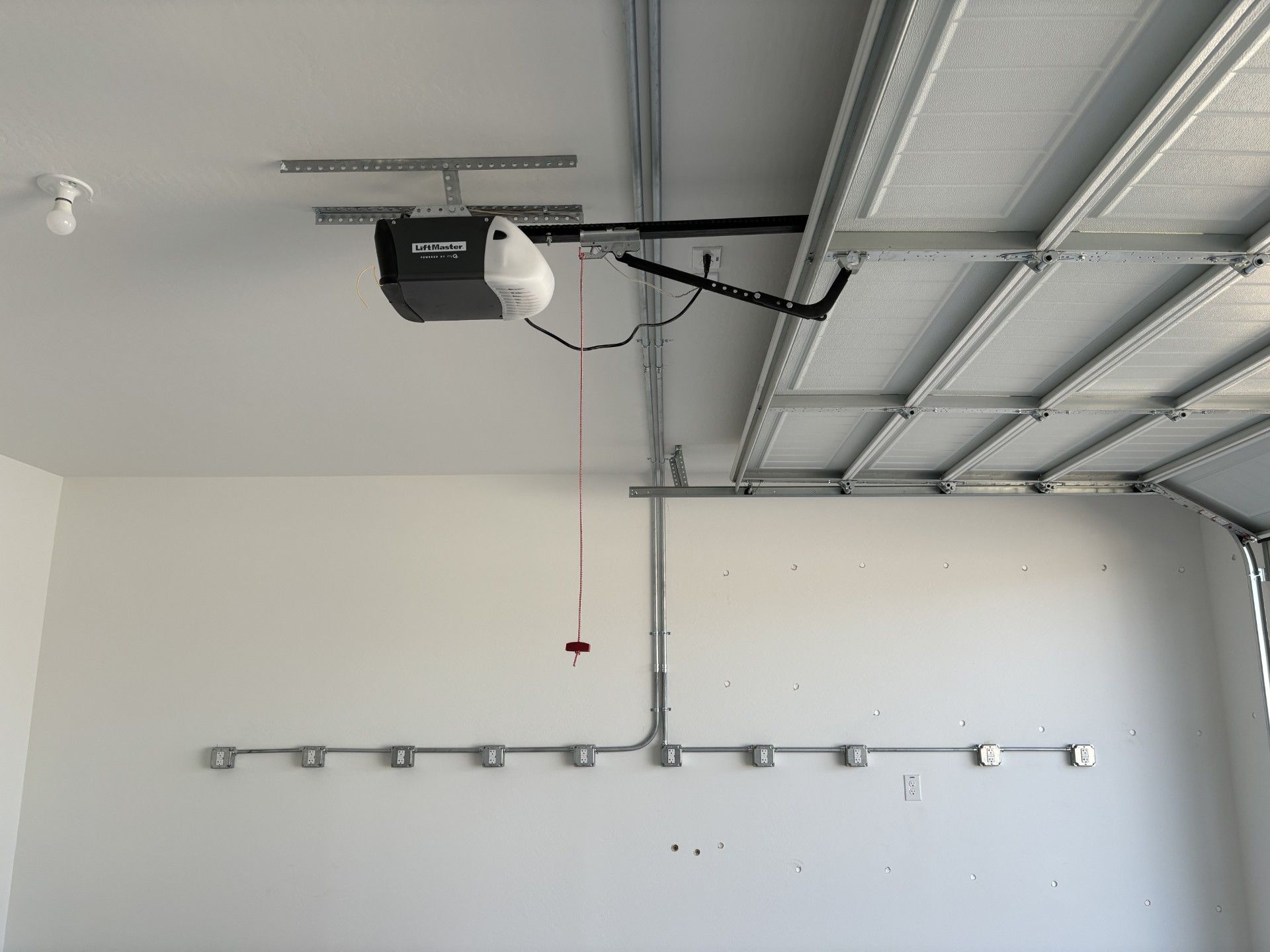 Garage interior with a garage door opener, white walls, and a row of electrical boxes.