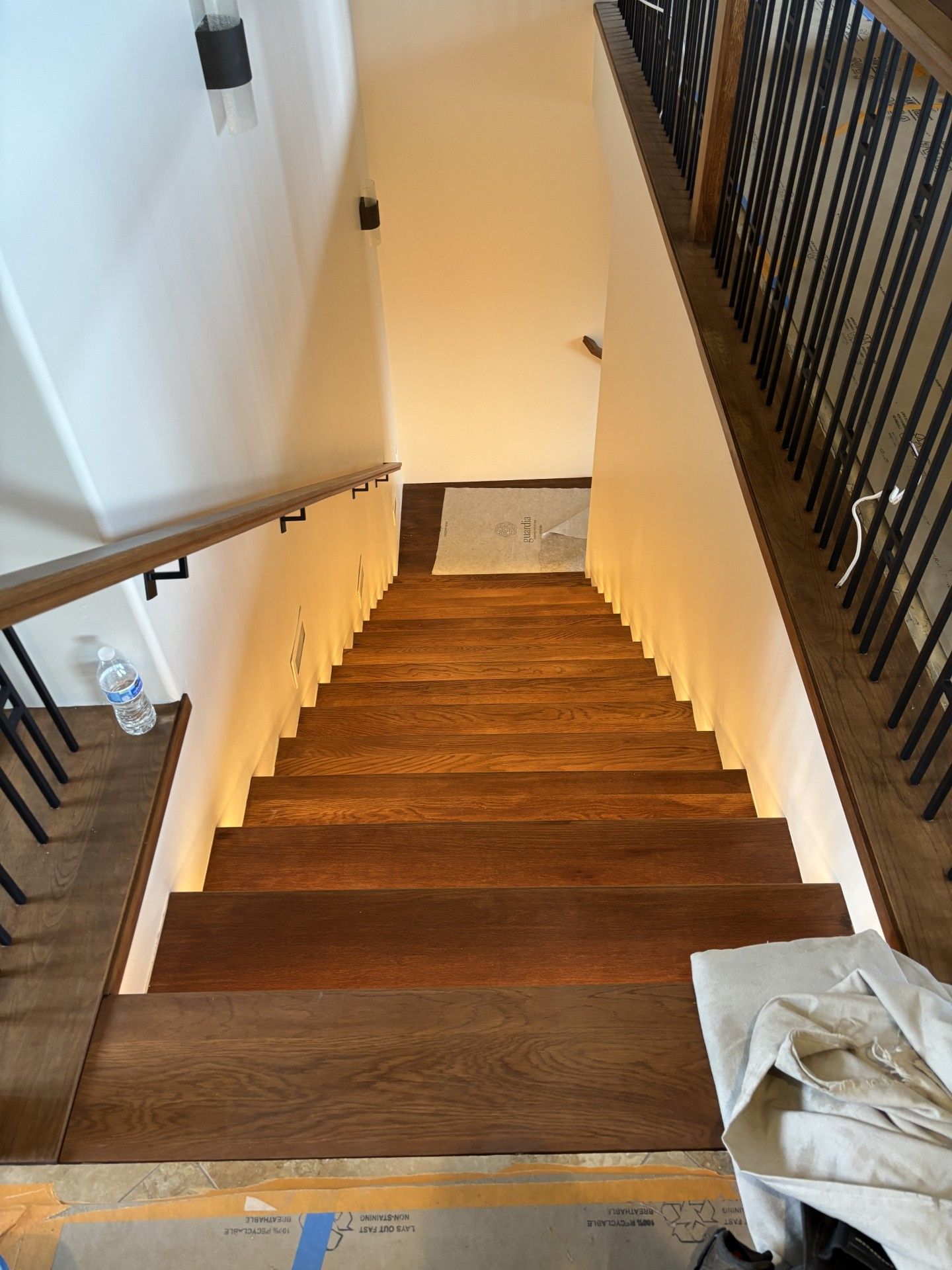 Wooden staircase with under-step lighting, dark wood steps, and black metal railings.