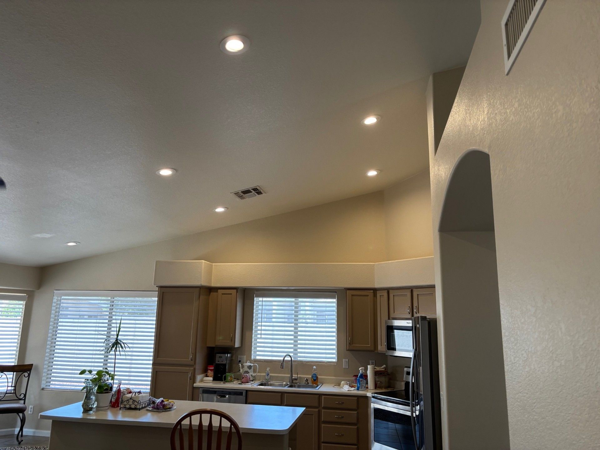 Kitchen interior with recessed lighting, light brown cabinets, and a kitchen island.