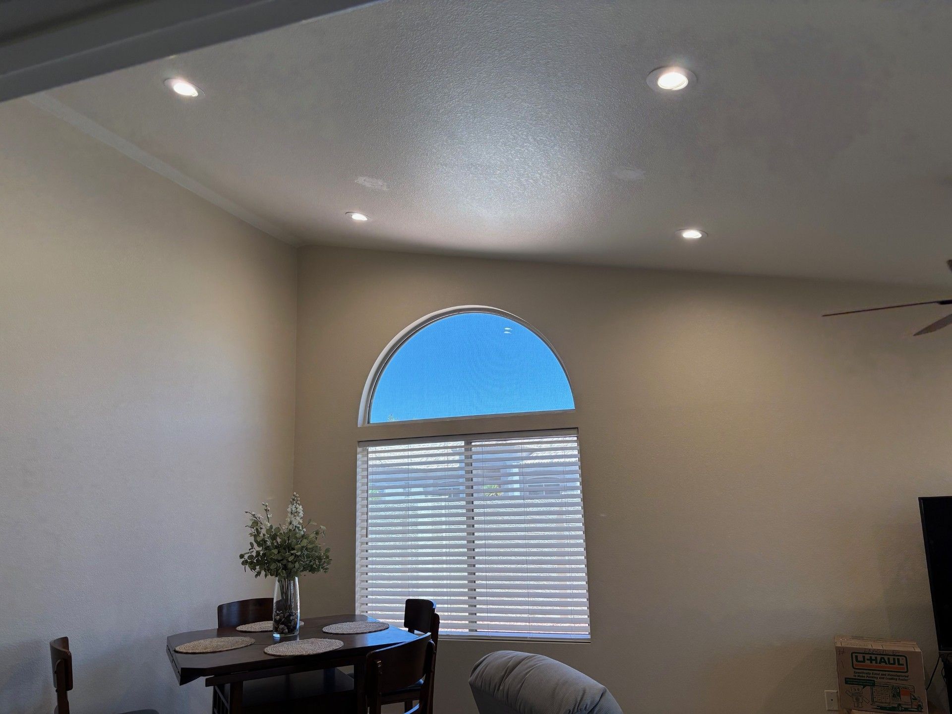 Interior view: dining area with arch window, blue sky visible, recessed lighting, table set for dining.