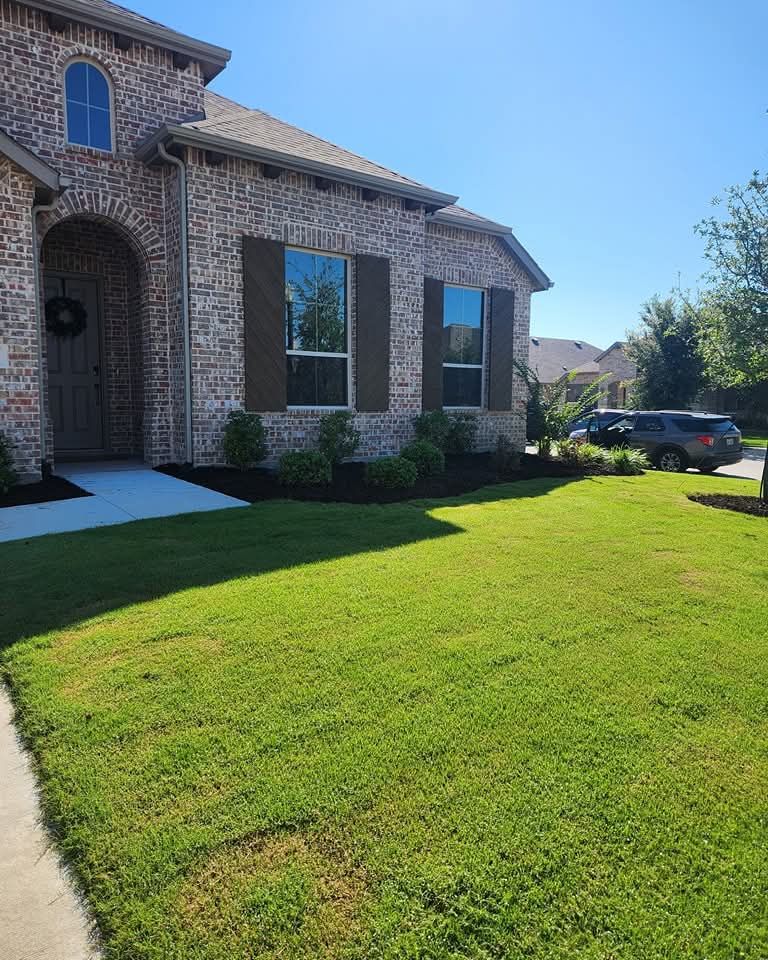 A brick residential house with brown shutters, a green lawn, and a sidewalk leading to the front entryway.
