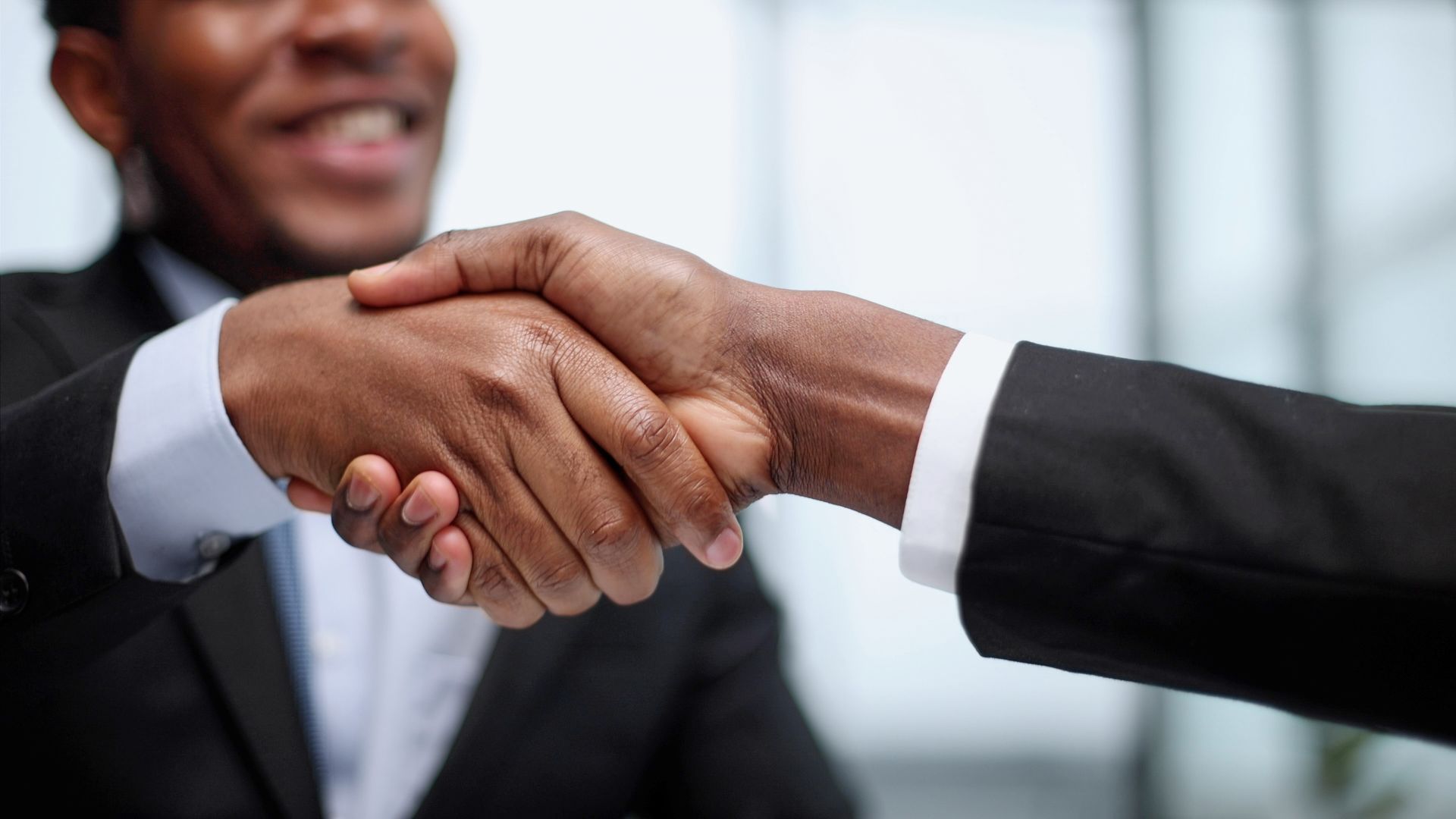 Two people in business suits shaking hands.