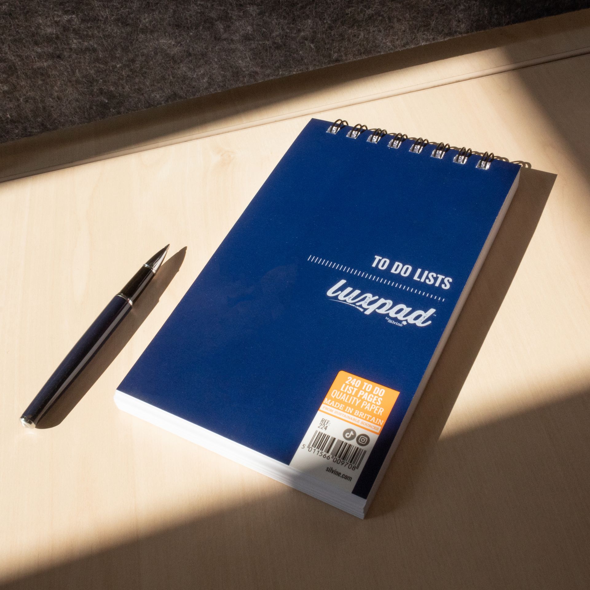 A To Do Pad by Silvine with a pen, on a desk with the sun shining down on them