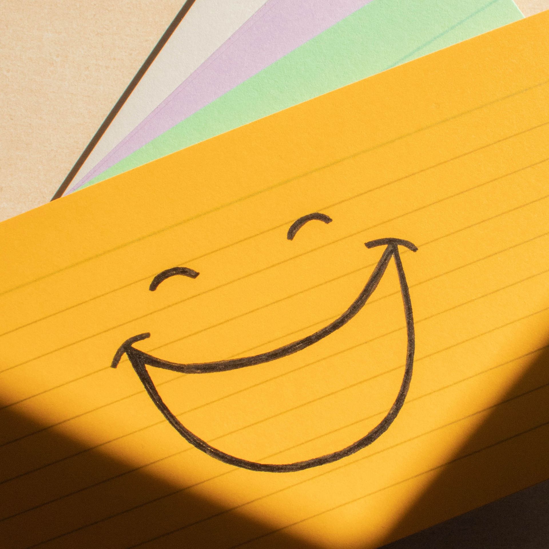 Assorted coloured flash cards with a smiley face drawn on.