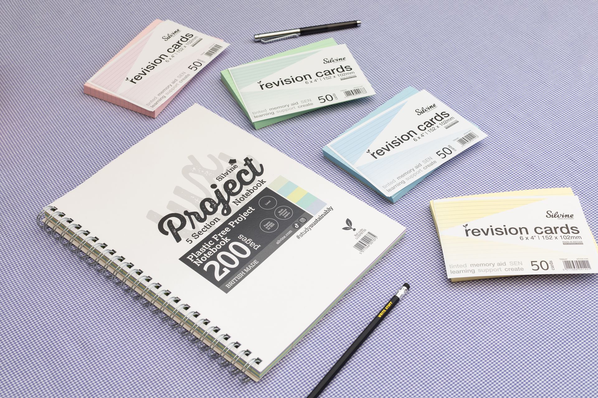 Tinted papers project book and SEN revision cards on purple background with pen and pencil.