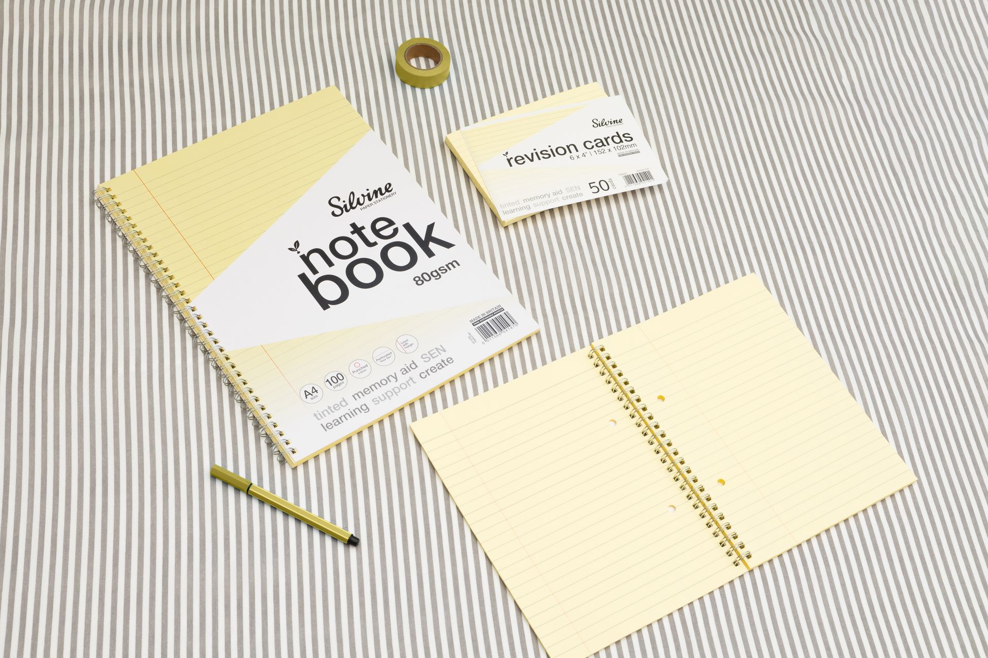 Yellow tinted notebook, revision card pack and yellow stationery accessories on a grey lined background.