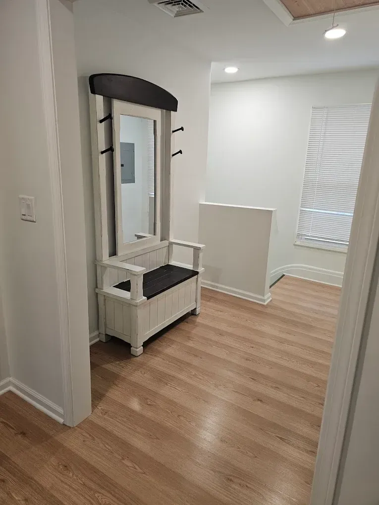 Yellow wet floor sign on polished floor, person cleaning with a floor buffer.