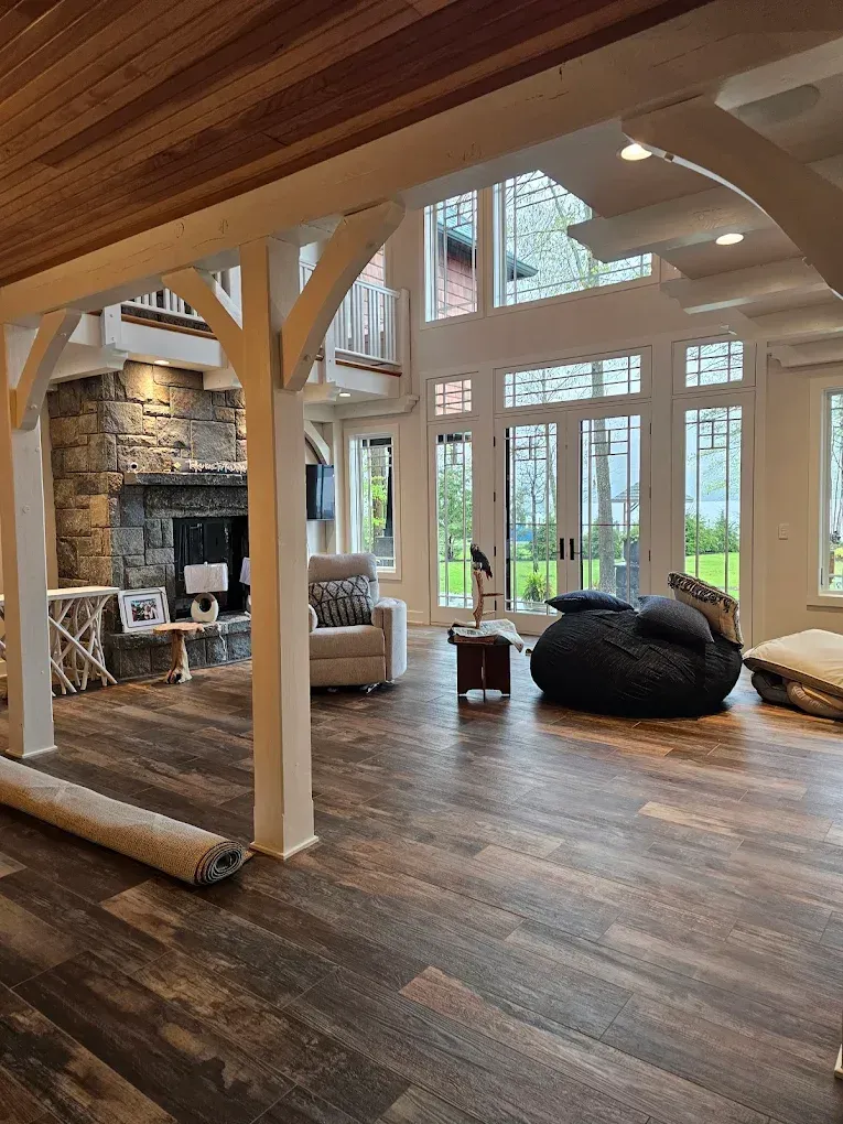 Spacious living room with stone fireplace, large windows, wood beams, and a beanbag chair.