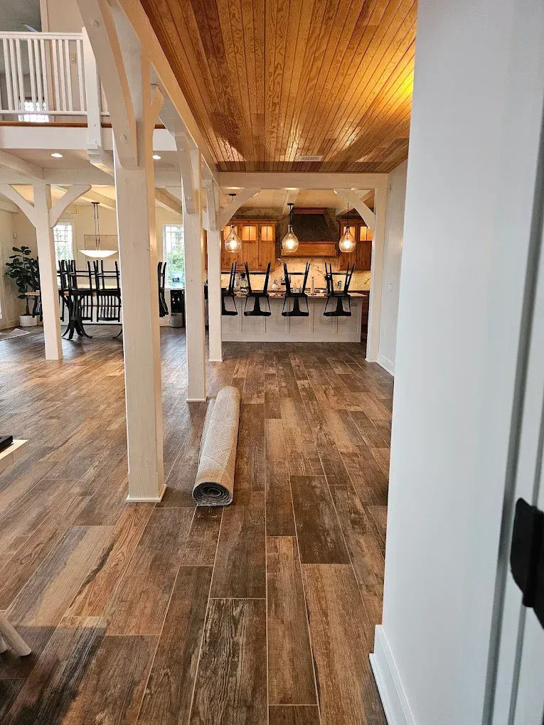 Modern conference room with long wooden table, black chairs, projector screen, and large windows.
