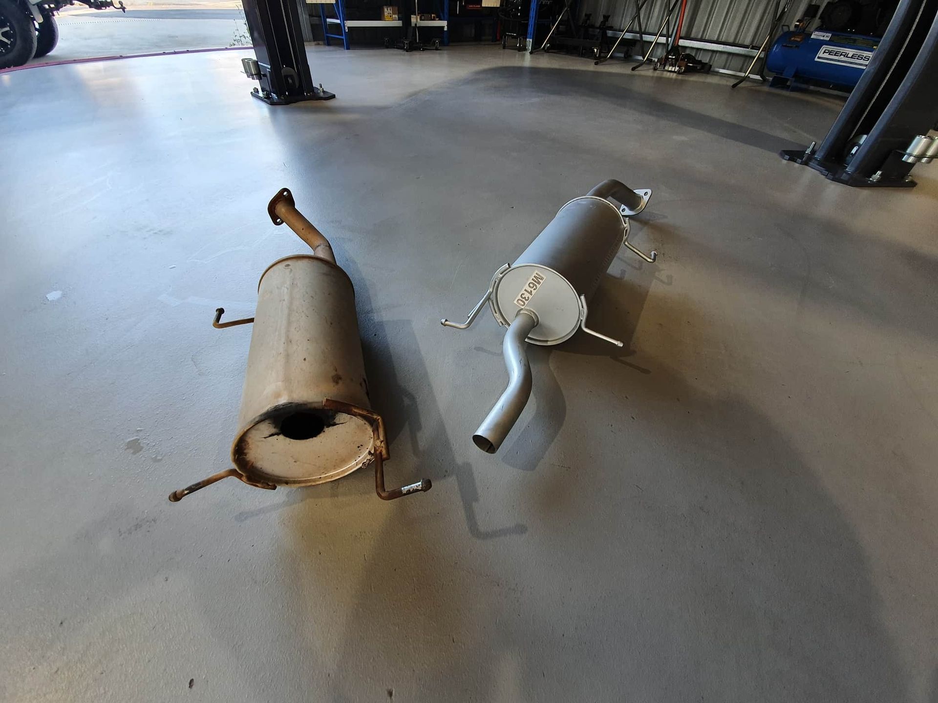 Two Exhaust Pipes Are Laying on the Floor in a Garage — OSP Automotive & Marine In Grafton, NSW
