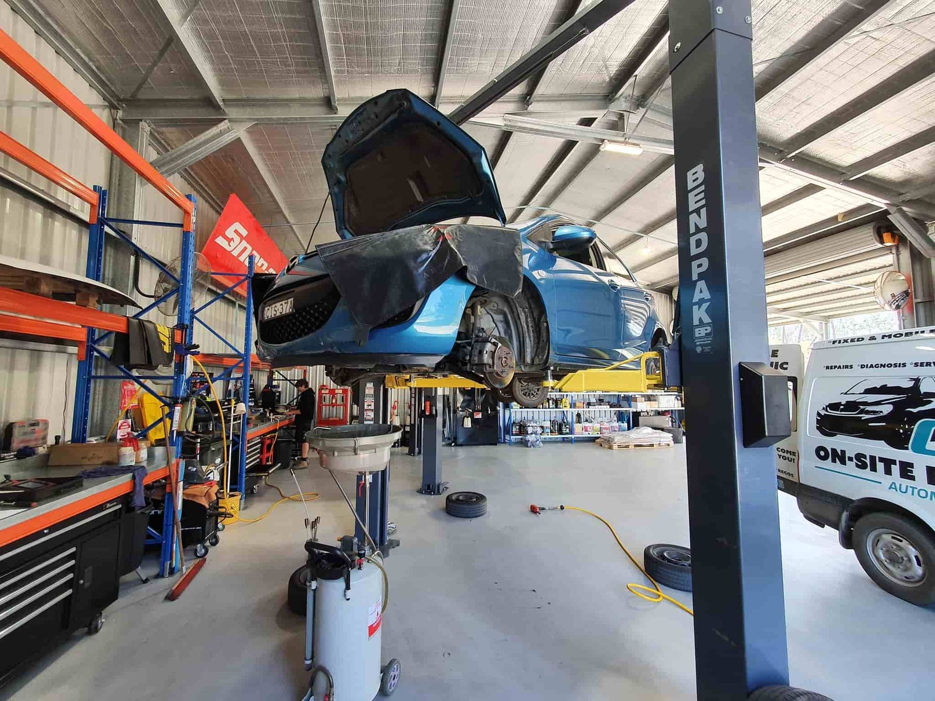 A Blue Car is Sitting on a Lift in a Garage — OSP Automotive & Marine In Grafton, NSW