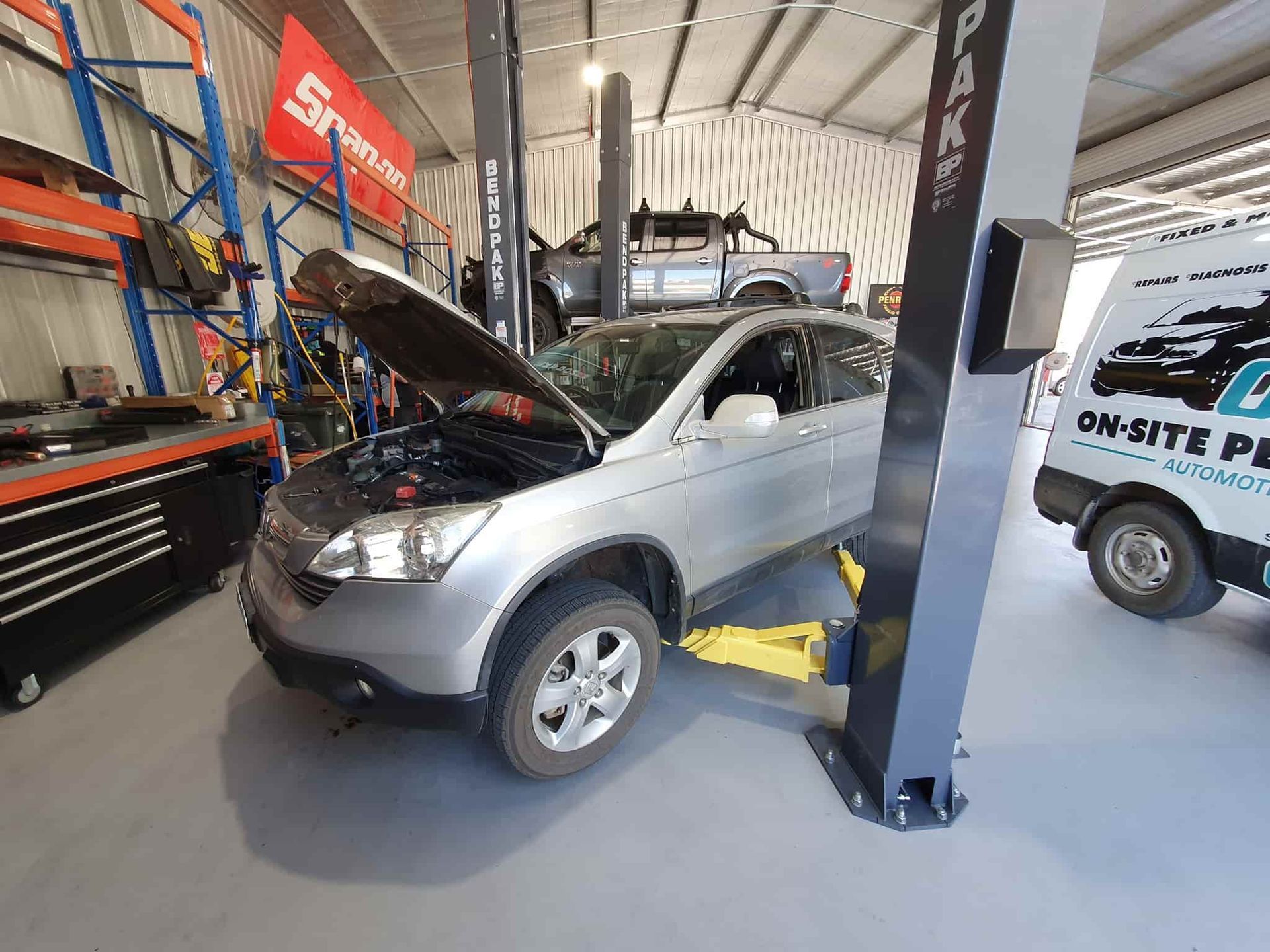 A Car is Sitting on a Lift in a Garage With Its Hood Open — OSP Automotive & Marine In Grafton, NSW
