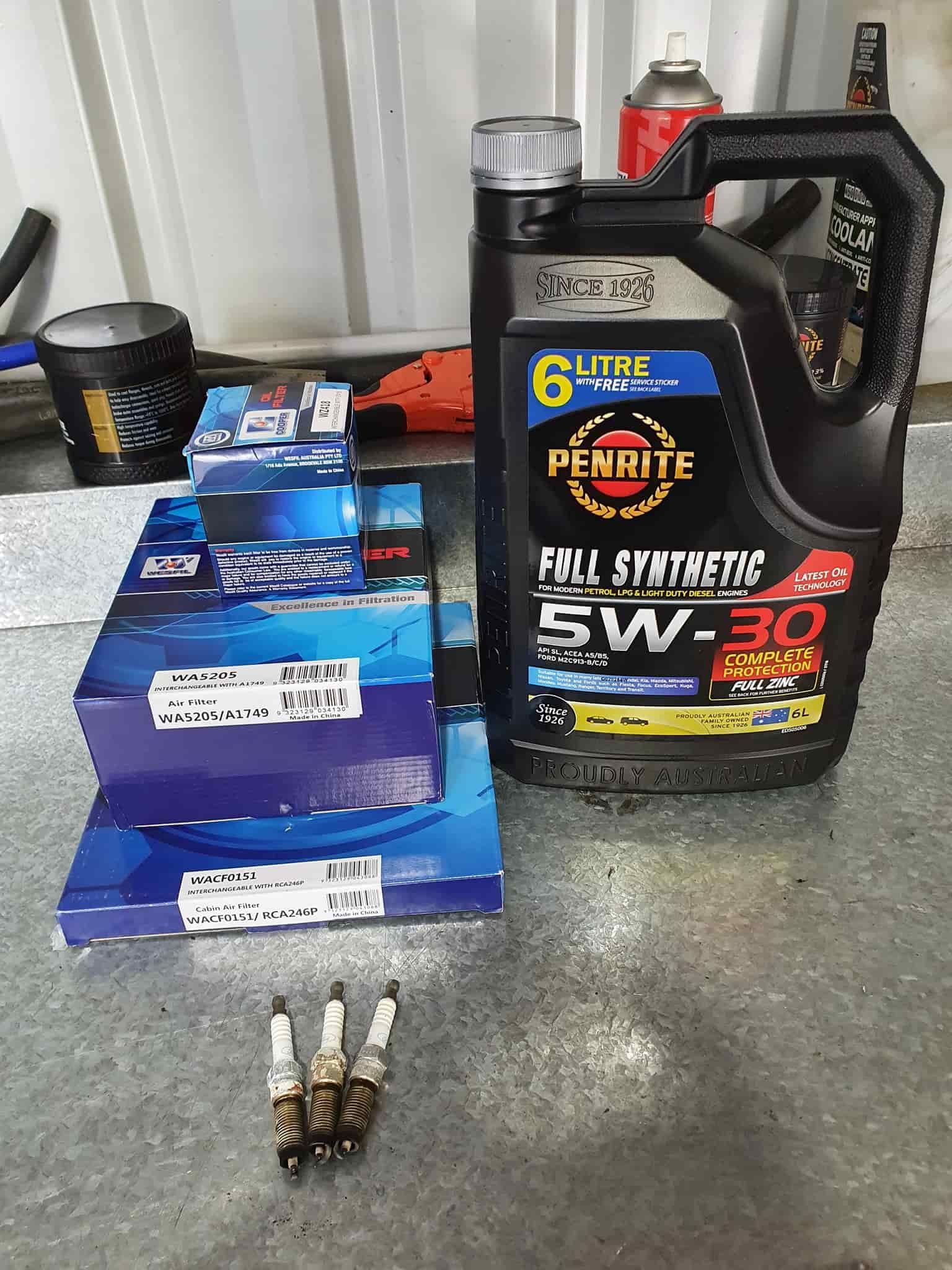 A Bottle of Oil and Spark Plugs Are Sitting on a Table — OSP Automotive & Marine In Grafton, NSW