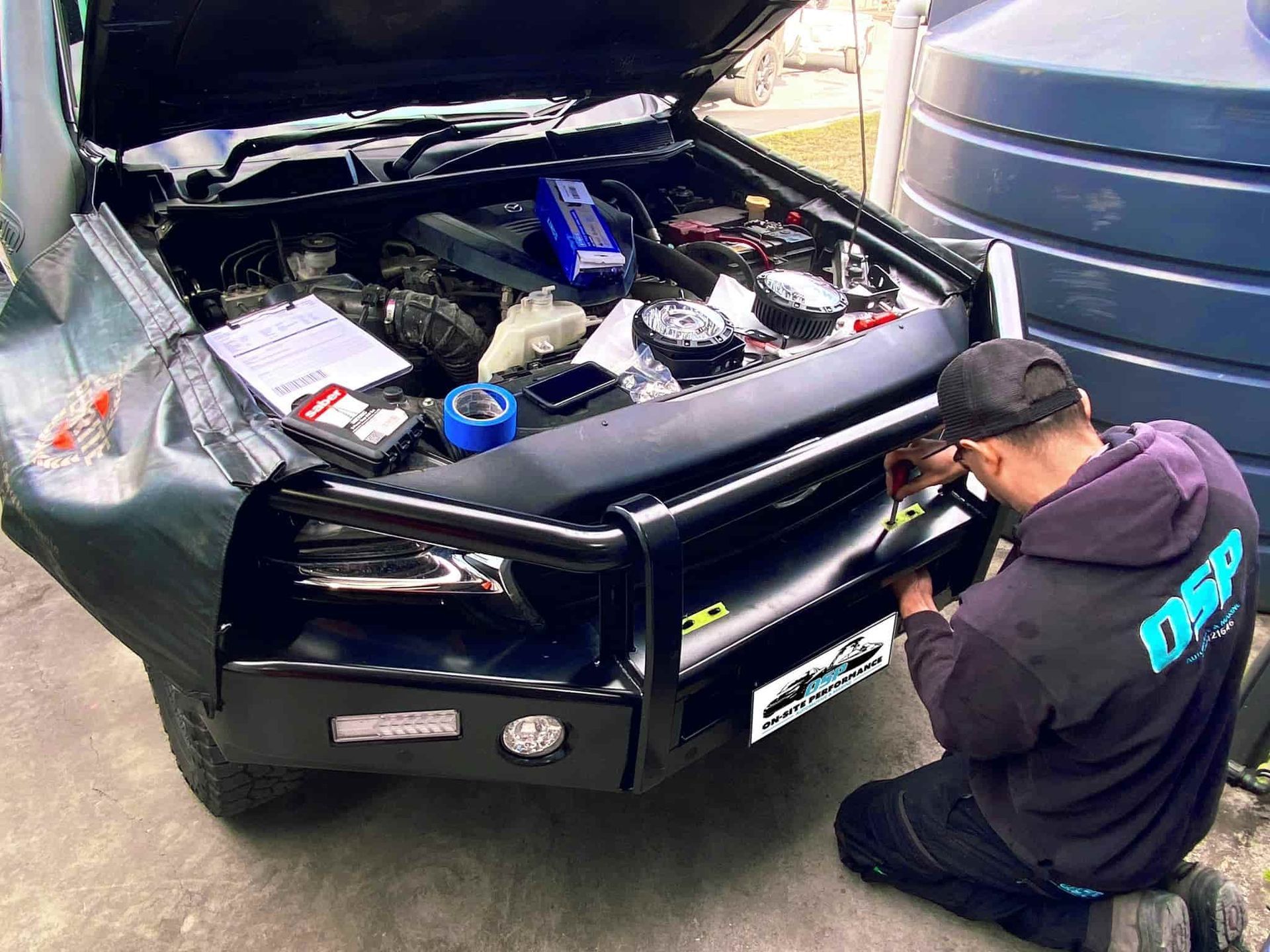 A Man is Working on the Front of a Car With the Hood Open — OSP Automotive & Marine In Grafton, NSW