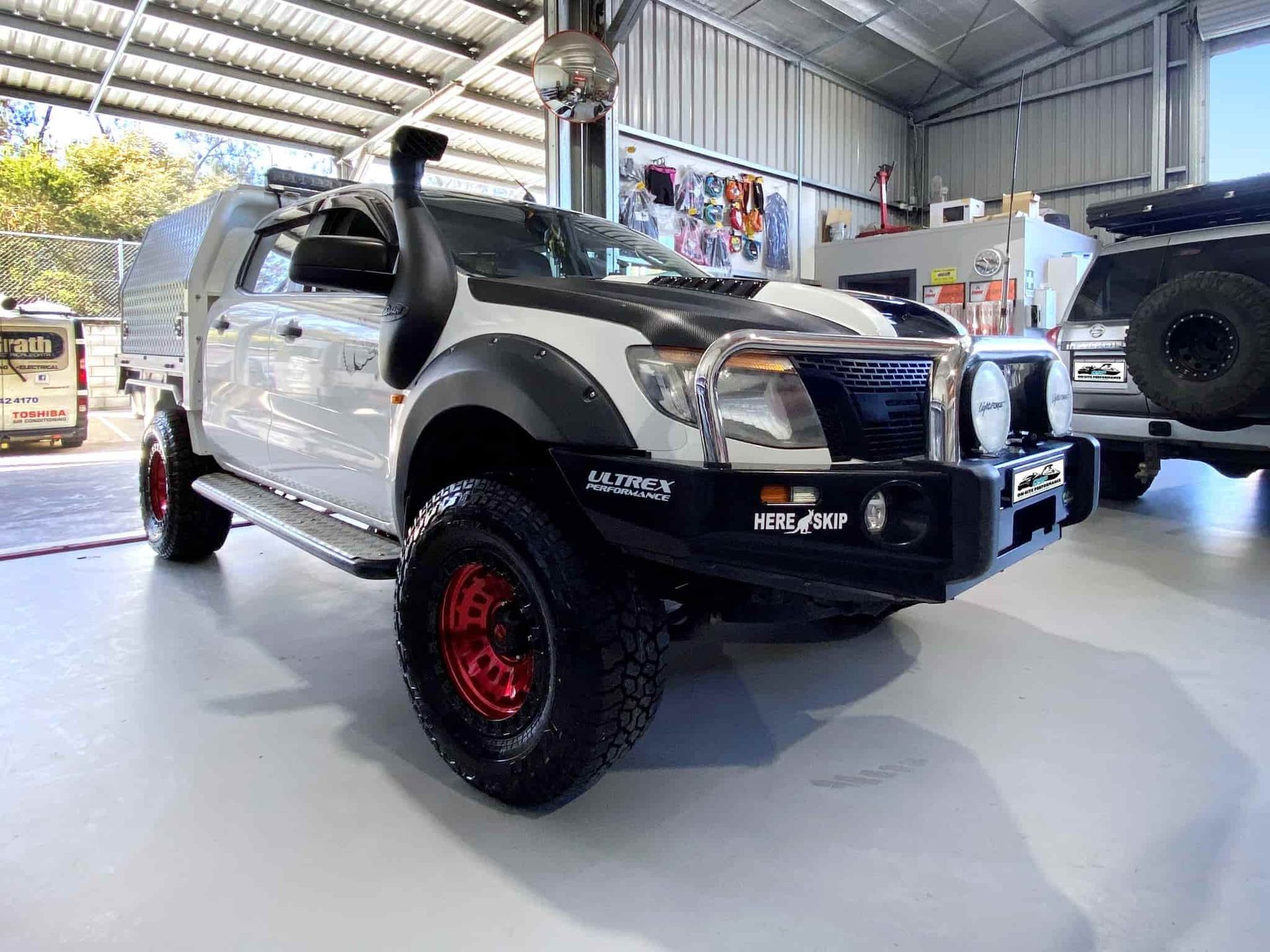 A White Truck With Red Wheels is Parked in a Garage — OSP Automotive & Marine In Grafton, NSW