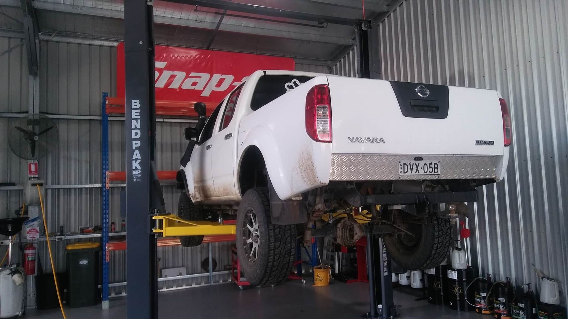 A White Truck is Sitting on a Lift in a Garage — OSP Automotive & Marine In Grafton, NSW