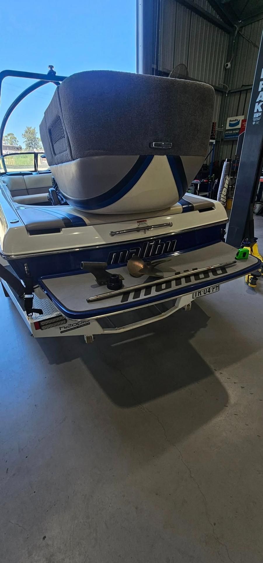 A White and Blue Boat is Parked in a Garage — OSP Automotive & Marine In Woolgoola, NSW