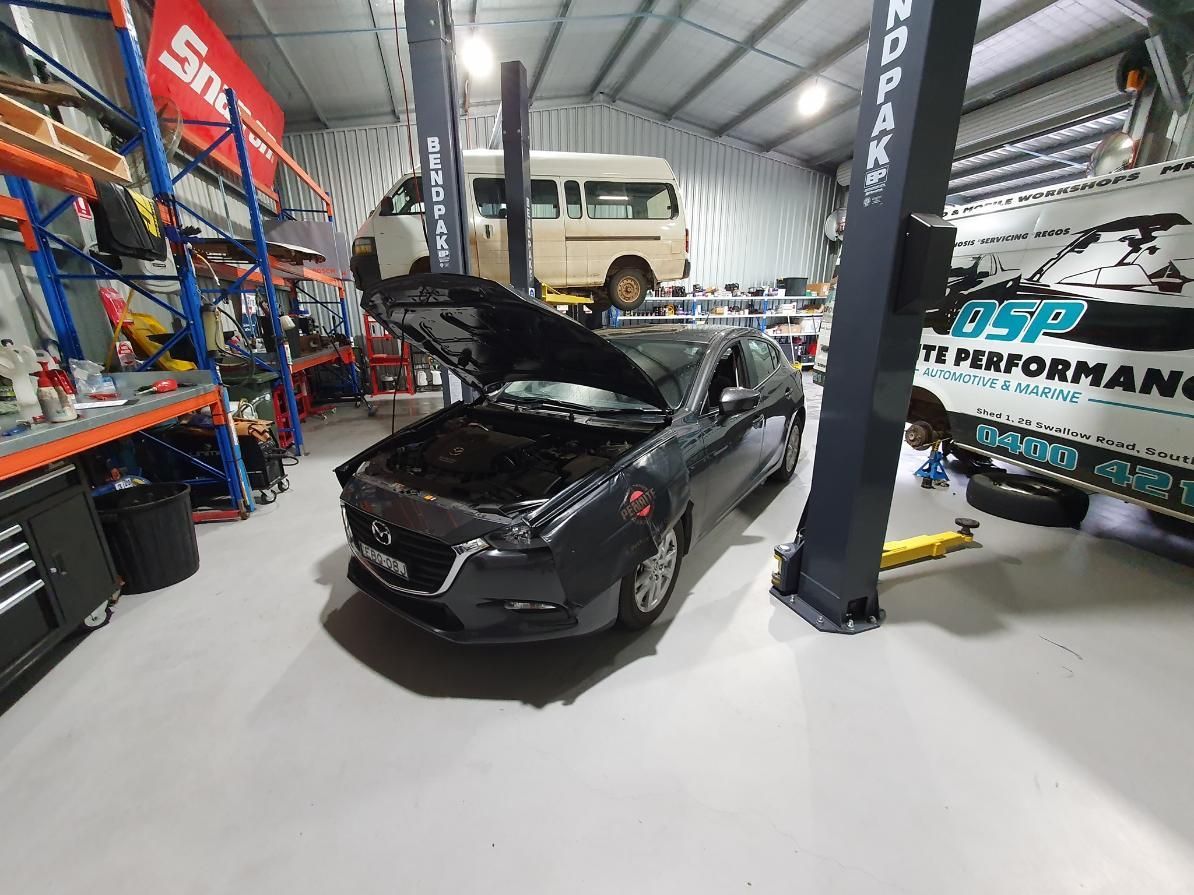 A Car is Sitting on a Lift in a Garage With Its Hood Open — OSP Automotive & Marine In Grafton, NSW