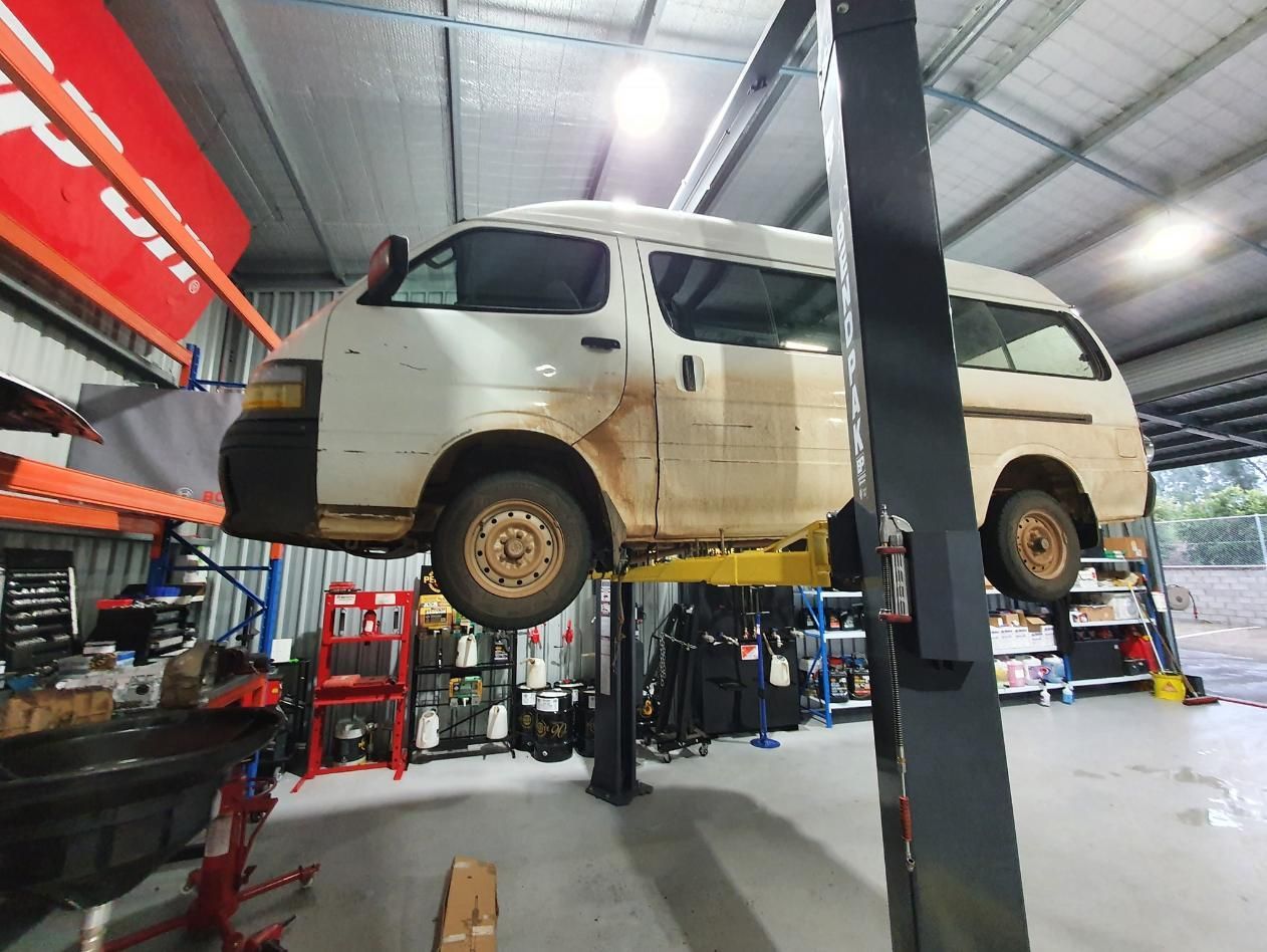A White Van is Sitting on Top of a Lift in a Garage — OSP Automotive & Marine In Grafton, NSW