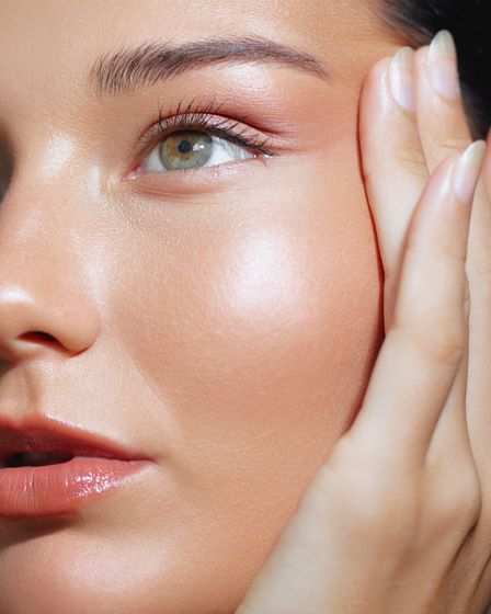 A close up of a woman 's face with her hand on her face.